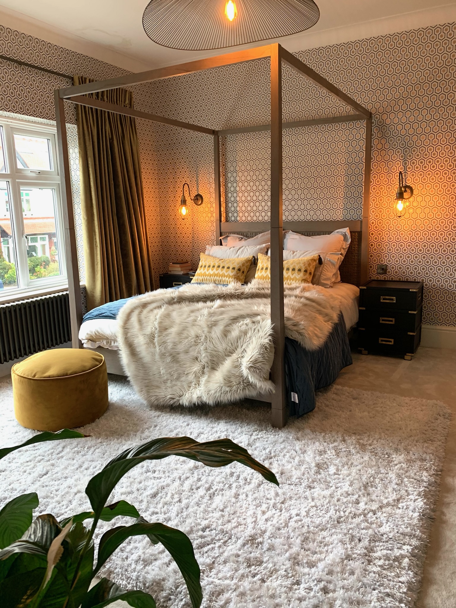 four poster bed with hexagonal print wallpaper in hale