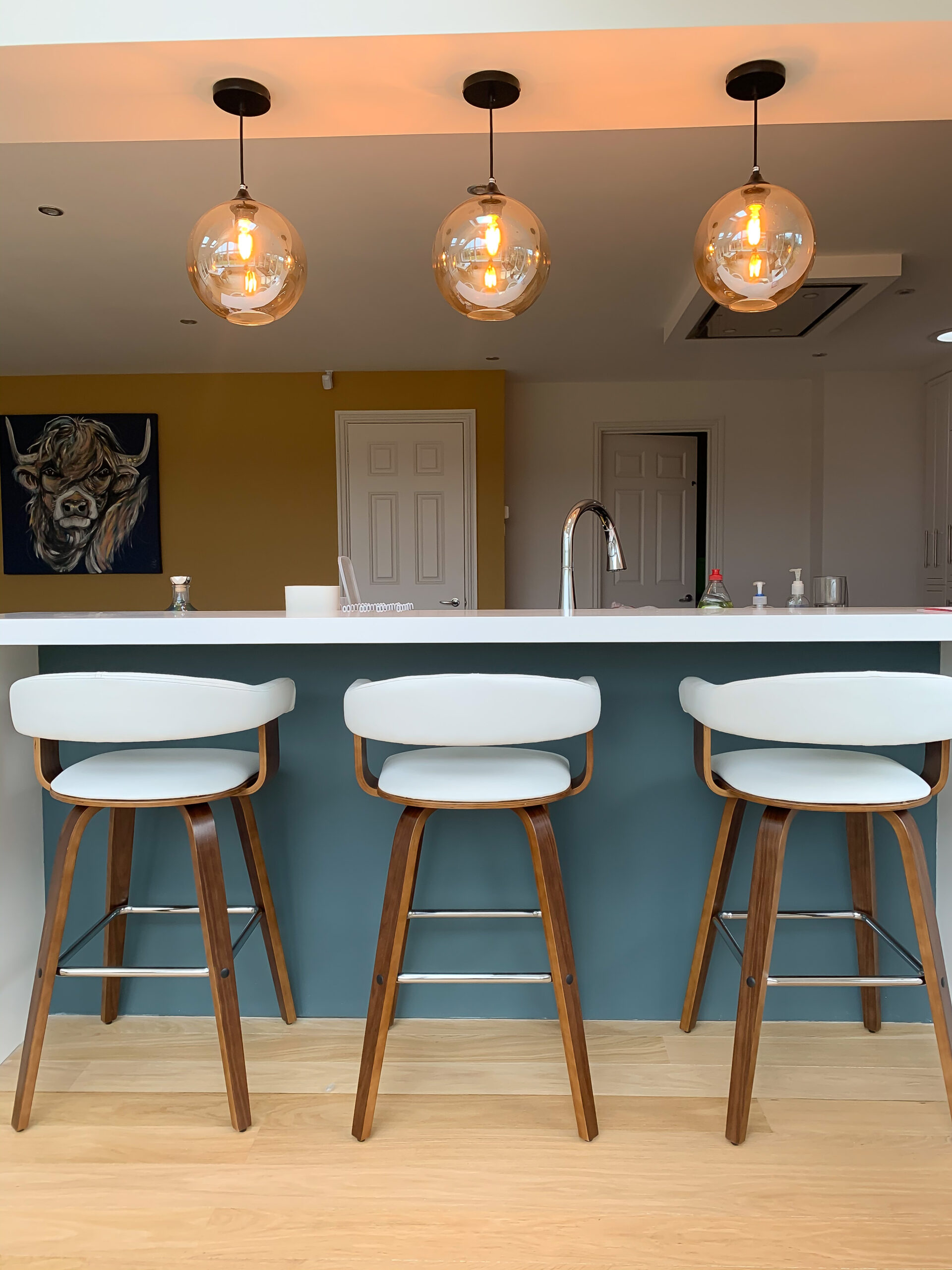 Balanced photo of three hanging light fittings over three bar stools in High Leigh