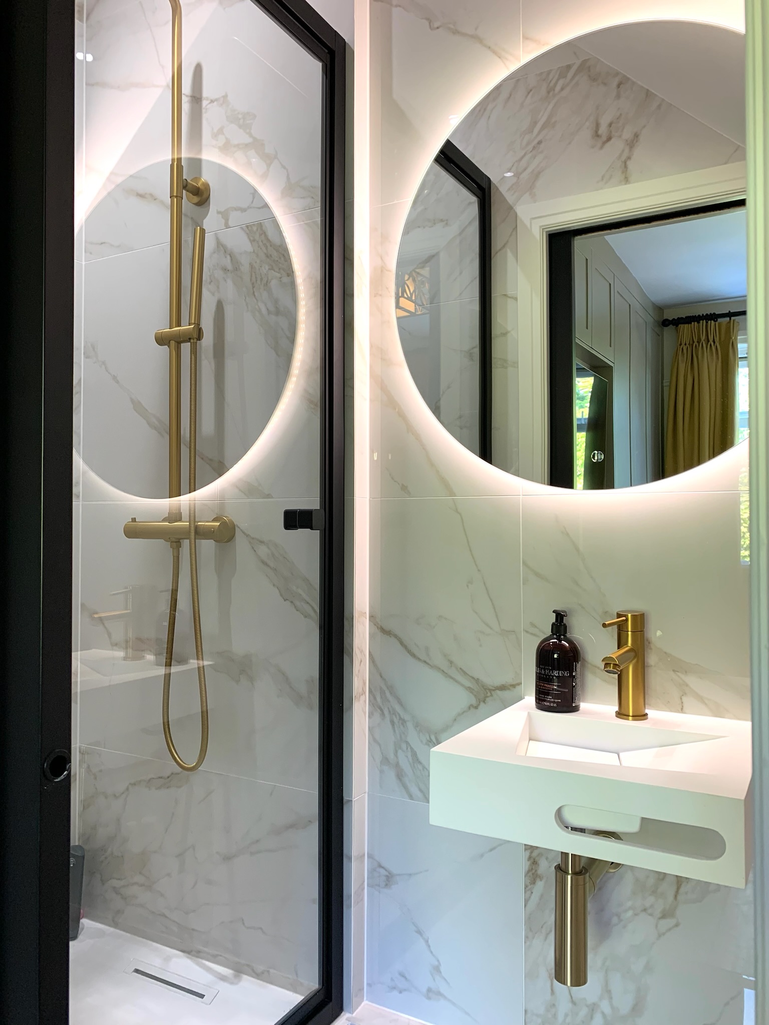 Modern round mirror in stylish designed gold and marble bathroom in Hale