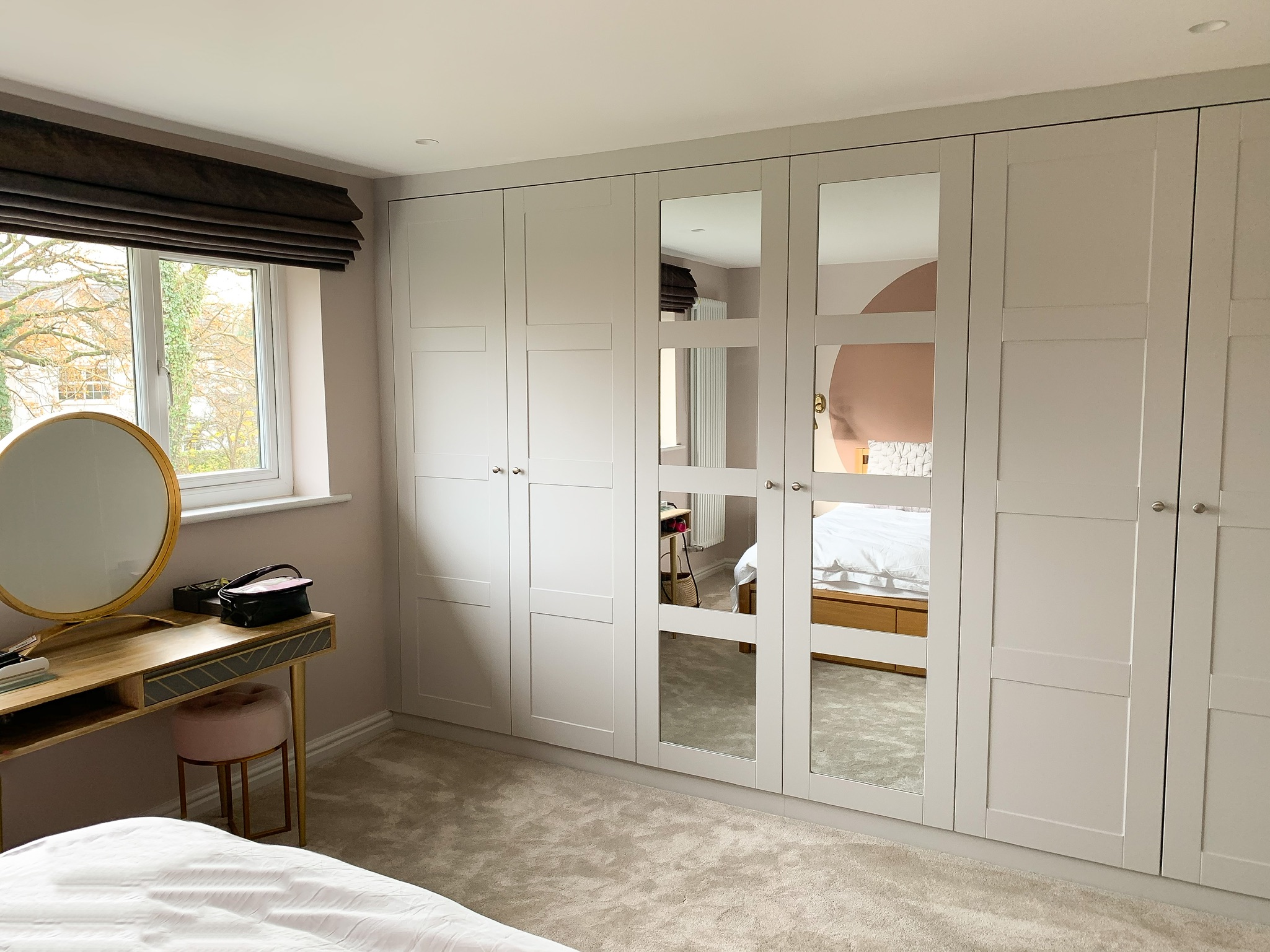 modern wardrobe with mirrors and dressing table with window view.